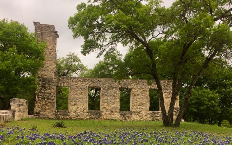 Image of Salado College ruins, a historic non-residential structure built in 1861. The ruins stand on a hill south of the creek, with the west wall and northeast corner of the east wall still visible amidst stone rubble. The walls display intricate stone construction once plastered with lime mortar and scored to resemble ashlar courses. Used as Thomas Arnold High School from 1890 to 1918, abandoned in 1924 after a fire. (RTHL)